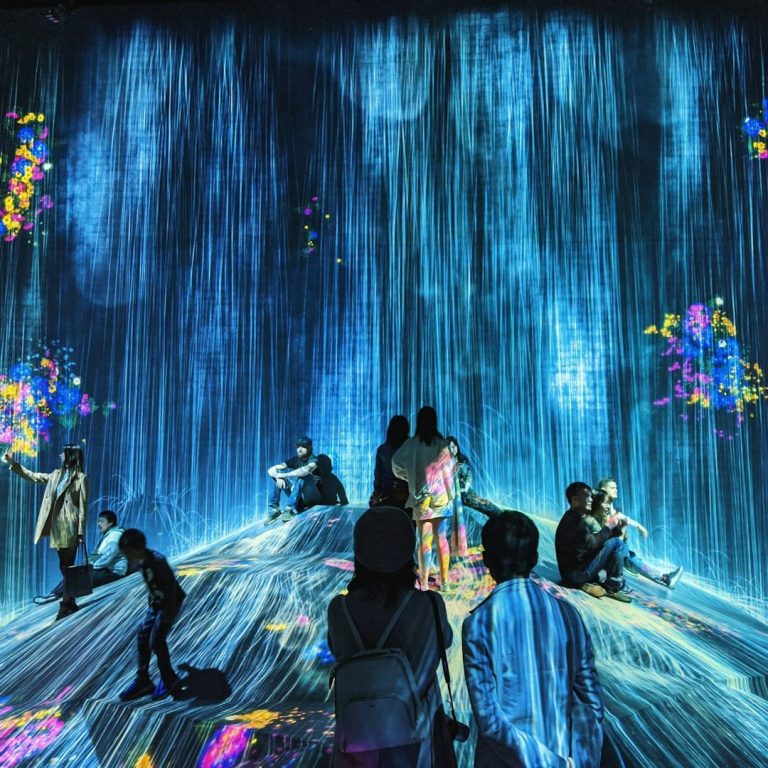 Menschen bewegen sich durch eine immersive digitale Lichtinstallation – Sinnbild für digitale Transformation, Innovation und Zukunftsräume